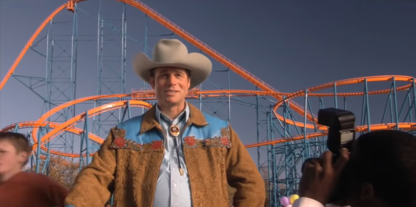 The coaster Titan in the background, in the foreground a man dressed as a cowboy