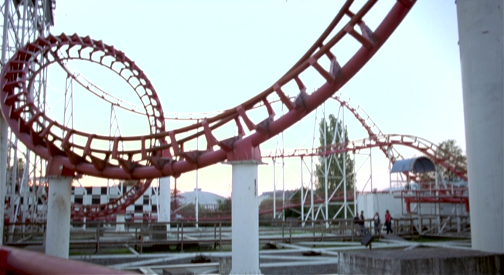 Corkscrew, you can see the lift hill and corkscrew on the left of the image, the characters are walking on a path through the middle.