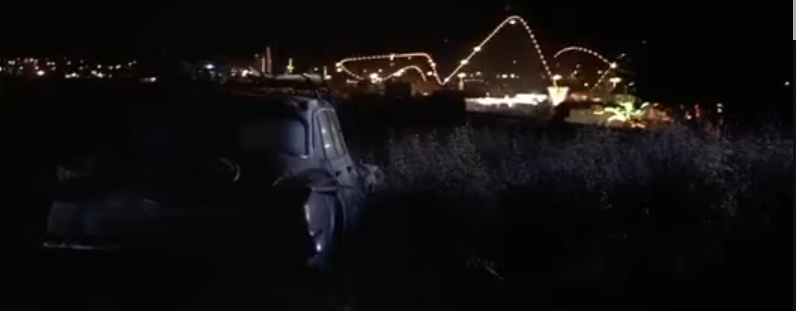 A car on a lovers lookout at night, in the background you can see the backside of Giant Dipper. Its track is lit by string lights.